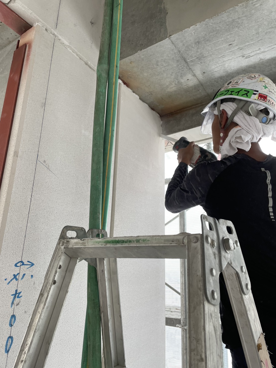 外壁パネル付近で電動工具を使用する職人